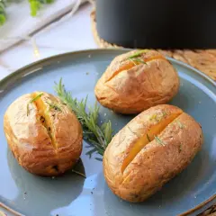 Tres patatas asadas airfryer doradas y crujientes, adornadas con romero fresco, listas para disfrutar.