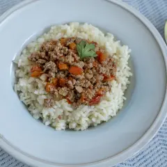 Un plato de arroz blanco cubierto con una sabrosa mezcla de arroz con carne picada, tomates y pimientos.