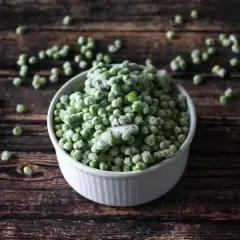 Un cuenco blanco lleno de guisantes congelados, perfecto para tus próximas recetas con guisantes congelados.