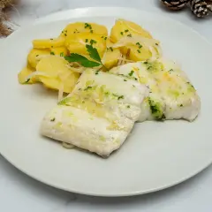 Dos filetes de merluza jugosos con patatas y cebolla, decorado con perejil fresco. Un plato delicioso y saludable.