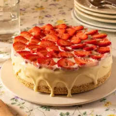 Tarta de frutas frescas cubierta de fresas y glaseado blanco cremoso.