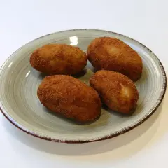 Cuatro croquetas de pollo de la abuela doradas y crujientes en un plato.
