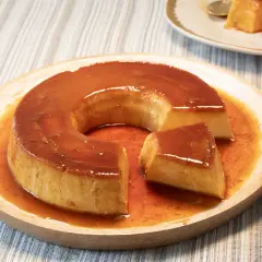 Un delicioso flan de leche condensada con caramelo líquido, servido en plato de madera.