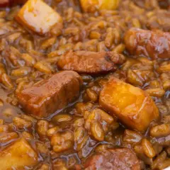 Un plato de arroz con acelgas y trozos de carne en una salsa oscura y apetitosa.