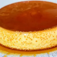 Delicioso flan de queso Philadelphia con caramelo líquido, servido en un plato blanco con diseño azul.