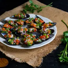 Mejillones a la vinagreta, frescos y coloridos, servidos en una concha con picadillo de verduras.
