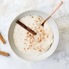 Un tazón cremoso de arroz con leche, espolvoreado con canela y una rama de canela. ¡Perfecto para aprender como hacer arroz con leche!