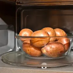 Patatas al microondas en un bol de cristal, listas para una cocción rápida y fácil.