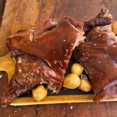 Delicioso cochinillo al horno, crujiente y jugoso, servido con patatas asadas.