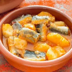 Un cuenco de barro con trozos de pescado y patatas en salsa, un delicioso all i pebre.