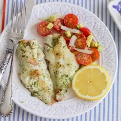 Deliciosa gallineta a la plancha con ensalada de tomate y aguacate, acompañada de un gajo de limón.