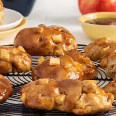 Buñuelos de manzana glaseados, con trozos de manzana visibles, sobre una rejilla.