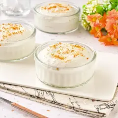 Tres ramequines de mousse de yogur con un toque de canela, servidos en una bandeja blanca.