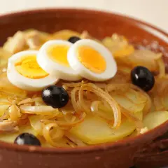 Bacalao a la portuguesa con patatas, cebolla, aceitunas negras y huevos duros en cazuela de barro.