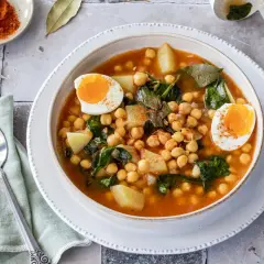 Un reconfortante plato de garbanzos con espinacas, patatas y huevos cocidos, espolvoreado con pimentón.