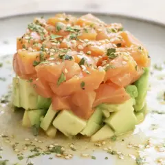 Delicioso tartar de salmón ahumado y aguacate, ideal para tus recetas con salmón ahumado. Adornado con sésamo y perejil.