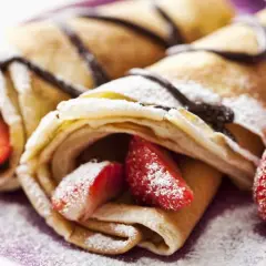 Deliciosos crepes sin huevo rellenos de fresas y bañados en chocolate, espolvoreados con azúcar glas.