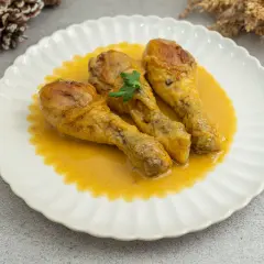 Tres jamoncitos de pollo dorados en una salsa cremosa, servidos en un plato blanco con un toque de perejil.