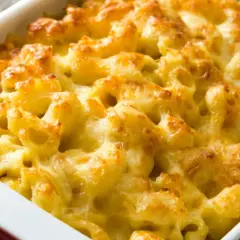 Mac and cheese cremoso y dorado, recién salido del horno en una fuente roja.