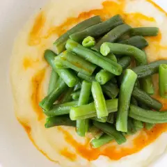 Judías verdes frescas y tiernas sobre un puré cremoso, con un toque de aceite de pimentón. Un plato sencillo y delicioso de judías verdes con patatas.