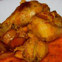 Sabroso pavo en salsa con cebollas, bañado en una rica y anaranjada salsa.