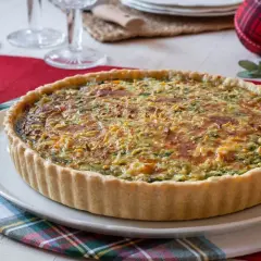 Un delicioso quiche de verduras con una corteza dorada y relleno cremoso, listo para ser disfrutado en una mesa festiva.