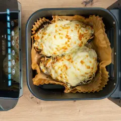 Dos berenjenas rellenas, cubiertas de queso derretido y dorado, listas para disfrutar tras su paso por la freidora de aire.