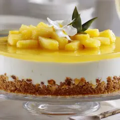 Deliciosa tarta de piña con trozos de fruta fresca y una capa de gelatina amarilla brillante, sobre una base crujiente.