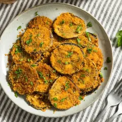 Berenjenas rebozadas con harina y huevo, doradas y crujientes, espolvoreadas con perejil fresco. Un plato delicioso y fácil de preparar.
