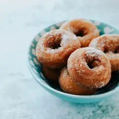 Rosquillas de Semana Santa espolvoreadas con azúcar, servidas en un cuenco azul.