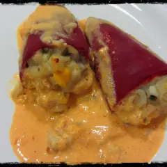 Dos pimientos del piquillo rellenos de gambas, cubiertos con una cremosa salsa rosada.