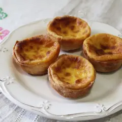 Cuatro deliciosos pastelitos de arroz con relleno cremoso y dorado, servidos en un plato blanco sobre un mantel bordado.