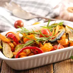 Deliciosas verduras al horno, como calabacín, pimientos y tomates cherry, con romero fresco, listas para servir.