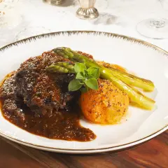 Carrilleras de ternera estofadas en salsa oscura, acompañadas de puré de boniato y espárragos trigueros.