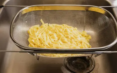 Espaguetis recién escurridos en un colador, listos para ser parte de deliciosas recetas de espaguetis.