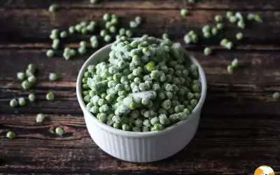 Un cuenco blanco lleno de guisantes congelados, perfecto para tus próximas recetas con guisantes congelados.