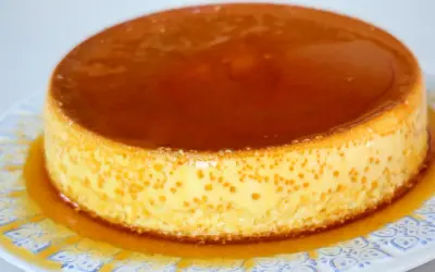 Delicioso flan de queso Philadelphia con caramelo líquido, servido en un plato blanco con diseño azul.