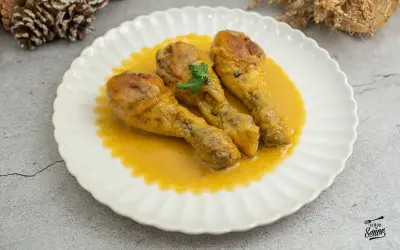 Tres jamoncitos de pollo dorados en una salsa cremosa, servidos en un plato blanco con un toque de perejil.