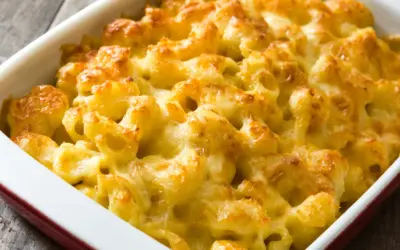 Mac and cheese cremoso y dorado, recién salido del horno en una fuente roja.