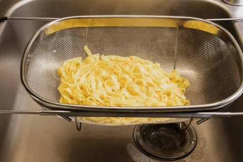Espaguetis recién escurridos en un colador, listos para ser parte de deliciosas recetas de espaguetis.