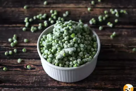 Un cuenco blanco lleno de guisantes congelados, perfecto para tus próximas recetas con guisantes congelados.