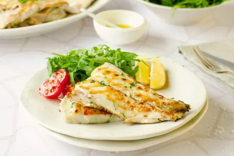 Deliciosa corvina a la plancha, servida con rúcula fresca, tomates cherry y gajos de limón. Un plato ligero y sabroso.