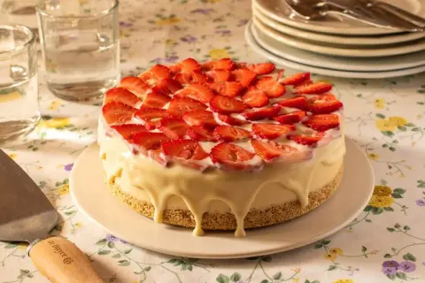 Tarta de frutas frescas cubierta de fresas y glaseado blanco cremoso.