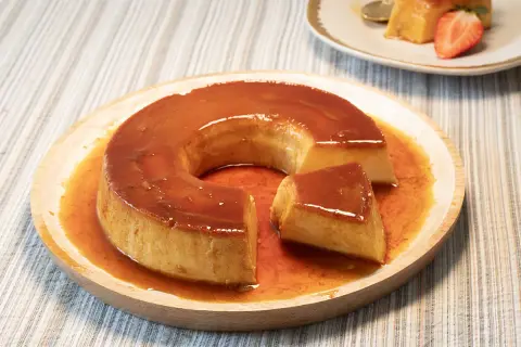 Un delicioso flan de leche condensada con caramelo líquido, servido en plato de madera.