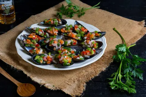Mejillones a la vinagreta, frescos y coloridos, servidos en una concha con picadillo de verduras.