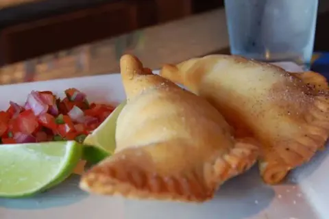 Dos empanadillas doradas con pico de gallo y limón. ¡Perfectos rellenos para empanadillas!