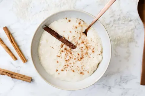 Un tazón cremoso de arroz con leche, espolvoreado con canela y una rama de canela. ¡Perfecto para aprender como hacer arroz con leche!