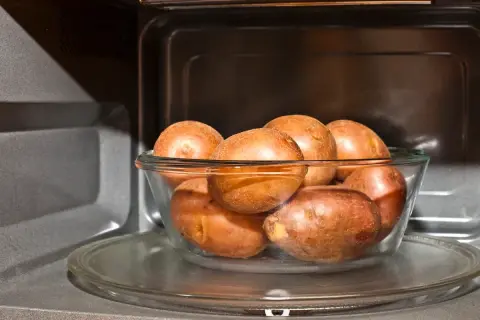 Patatas al microondas en un bol de cristal, listas para una cocción rápida y fácil.