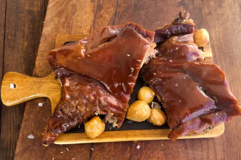 Delicioso cochinillo al horno, crujiente y jugoso, servido con patatas asadas.