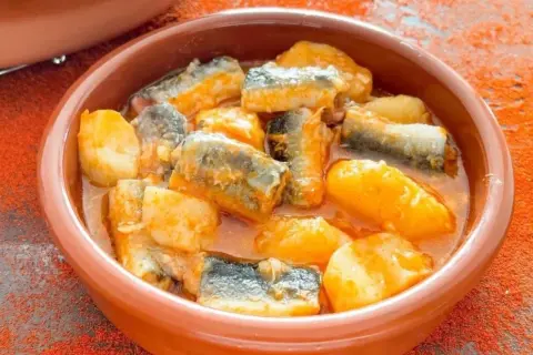 Un cuenco de barro con trozos de pescado y patatas en salsa, un delicioso all i pebre.